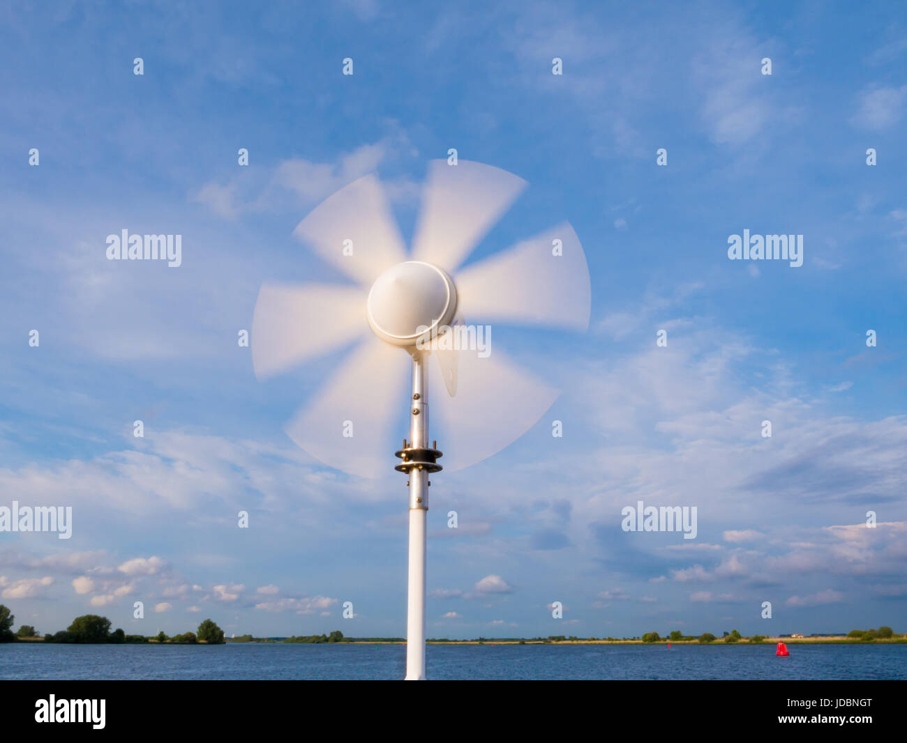 Marine wind turbine on sailing boat with turning blades using wind power to charge onboard batteries Stock Photo