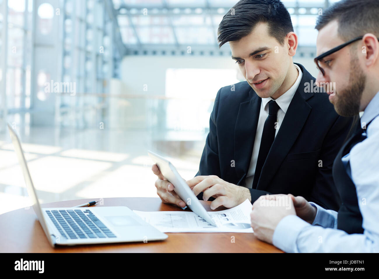 Portrait of two business partners using digital tablet and laptop in