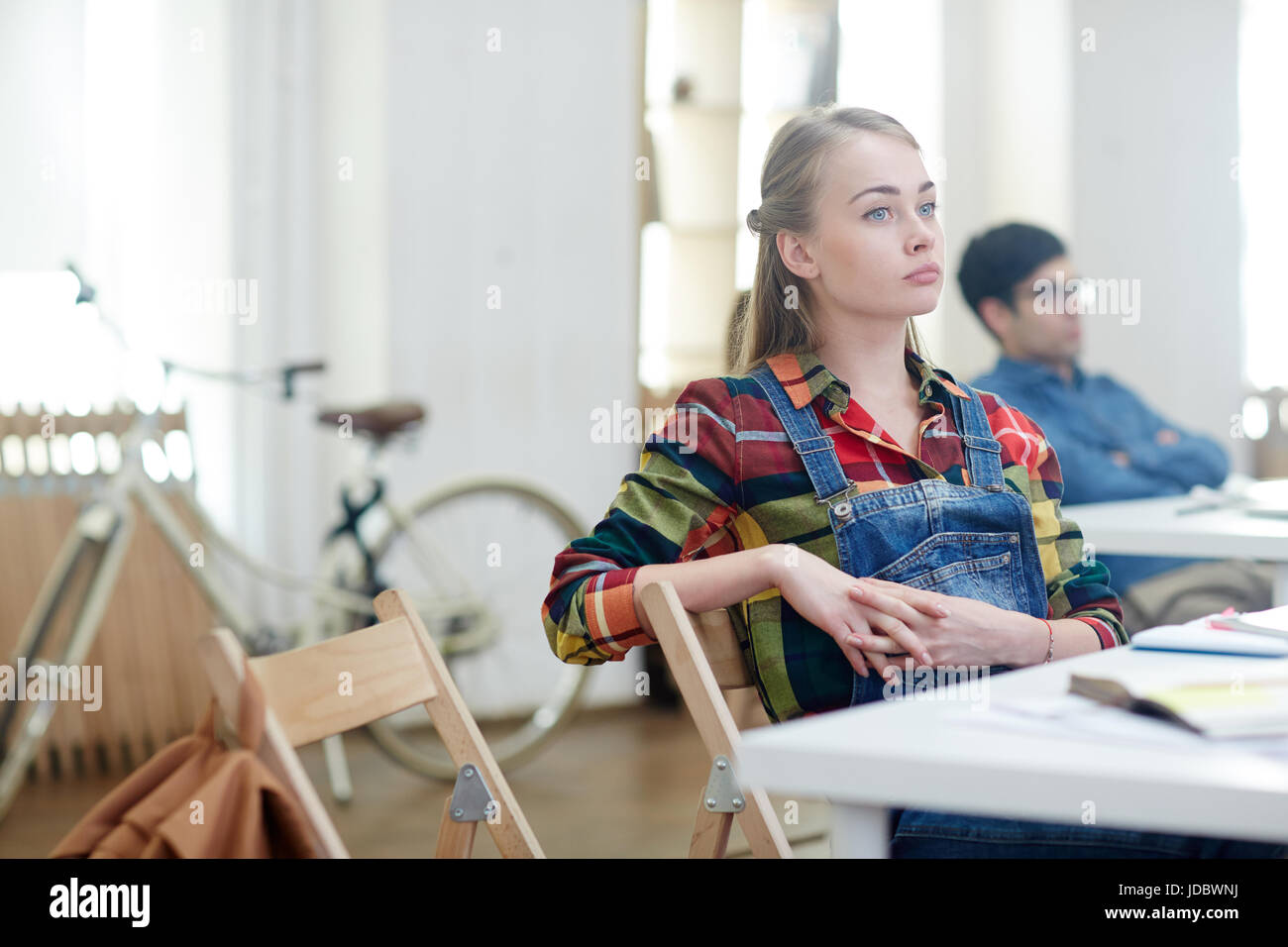 Absent minded girl sitting by desk at lesson Stock Photo