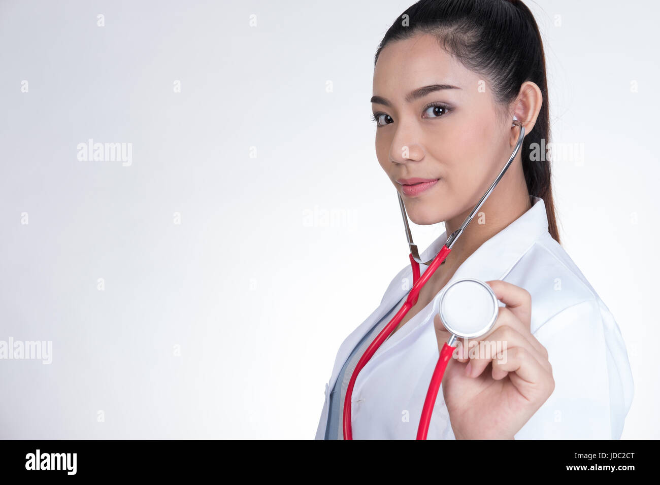 young female doctor showing stethoscope for checkup over white