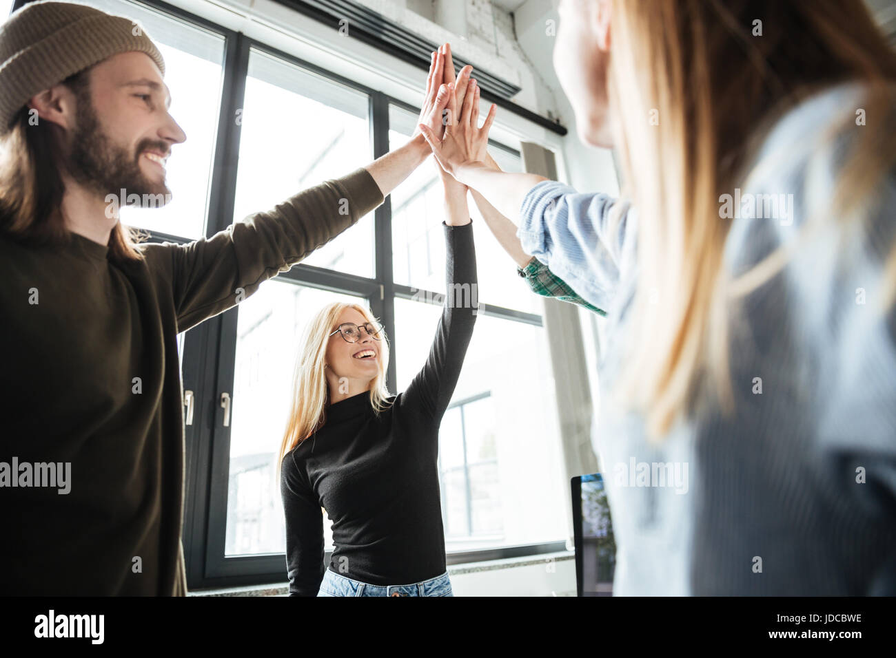 Picture of young happy colleagues in office give a high five to each ...