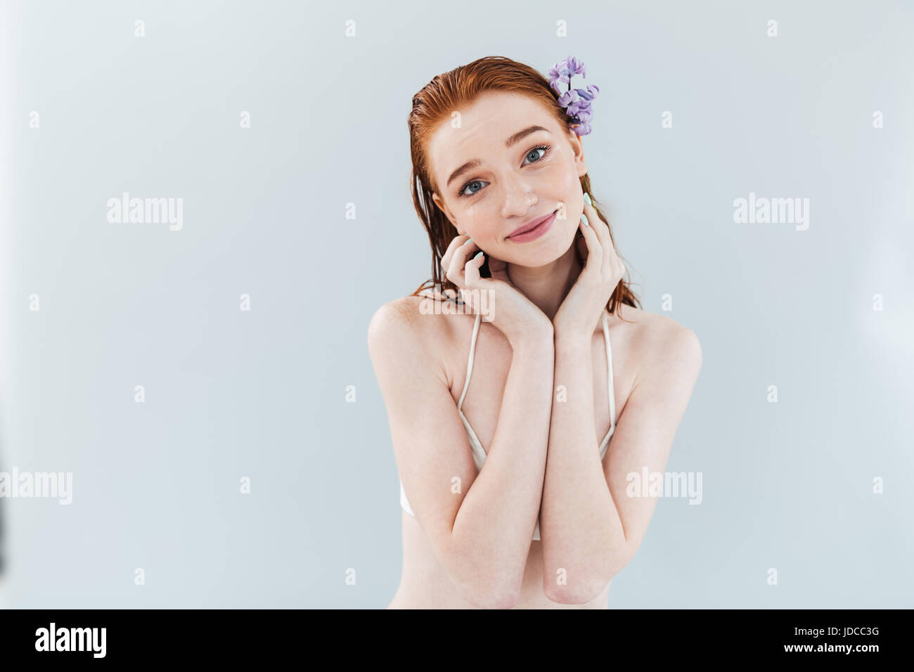 Close up portrait of a young cute ginger woman posing with flower in ...