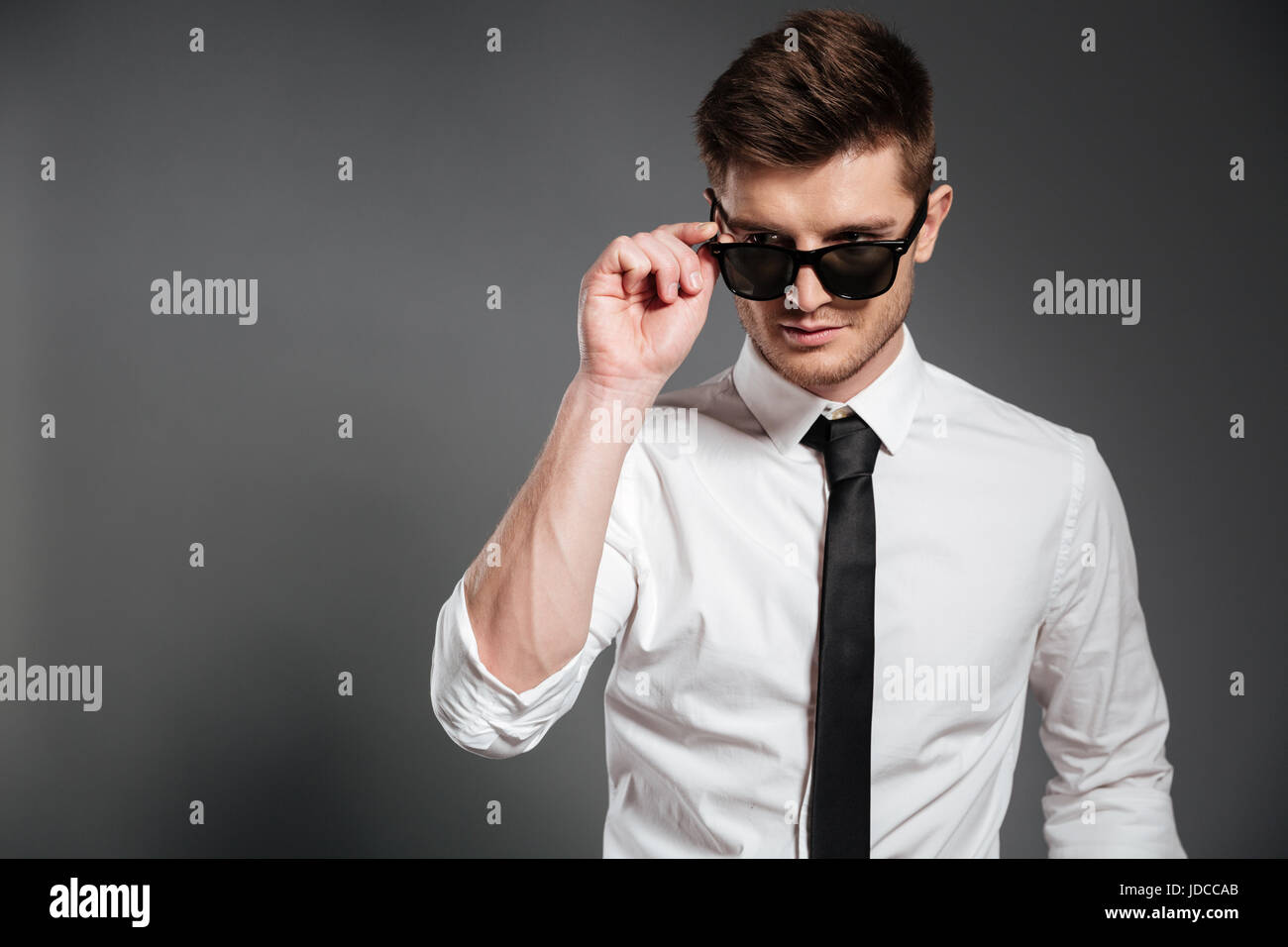Portrait of a young handsome guy in white shirt standing and posing ...