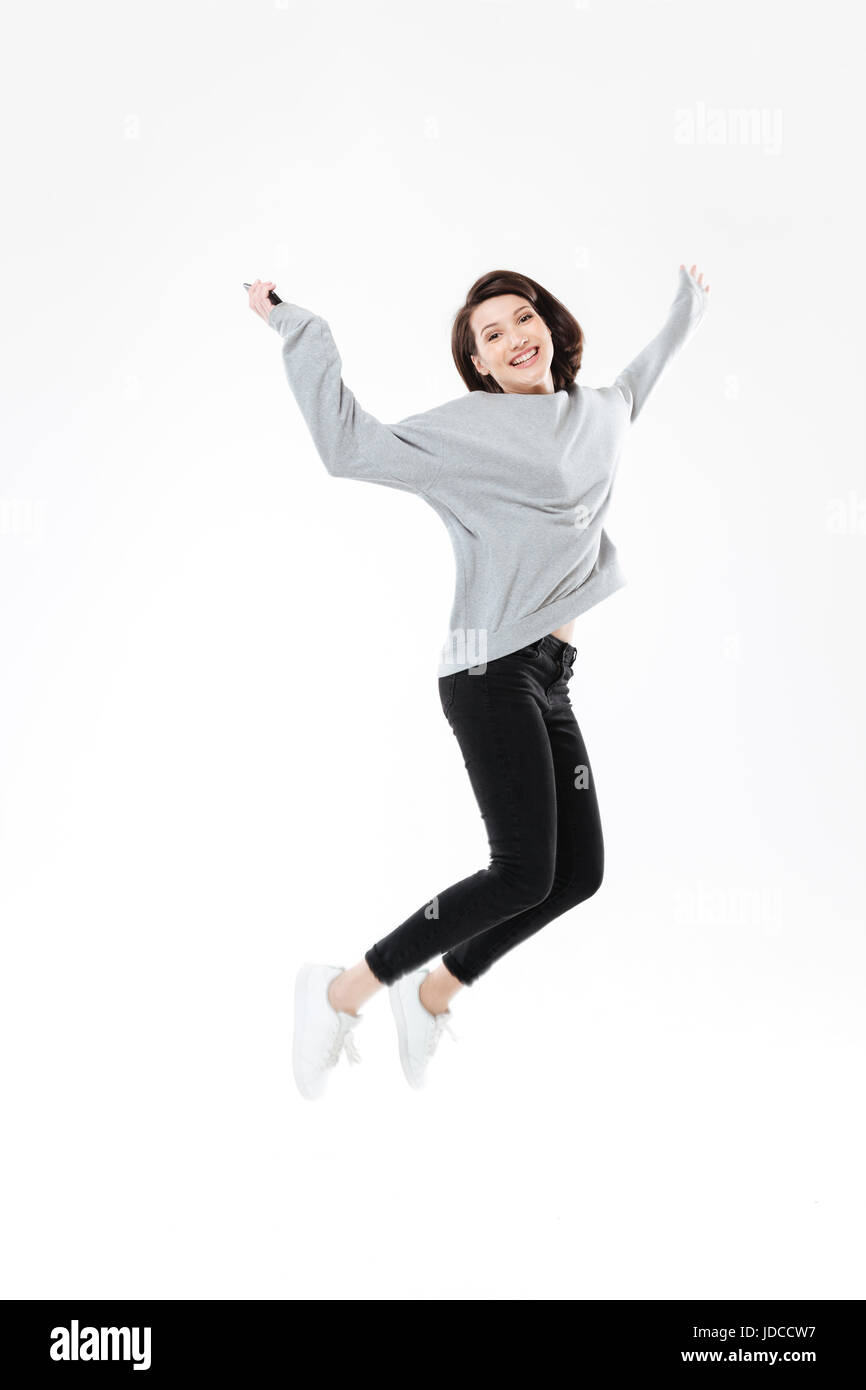 Full length portrait of a cheerful young girl jumping and celebrating ...