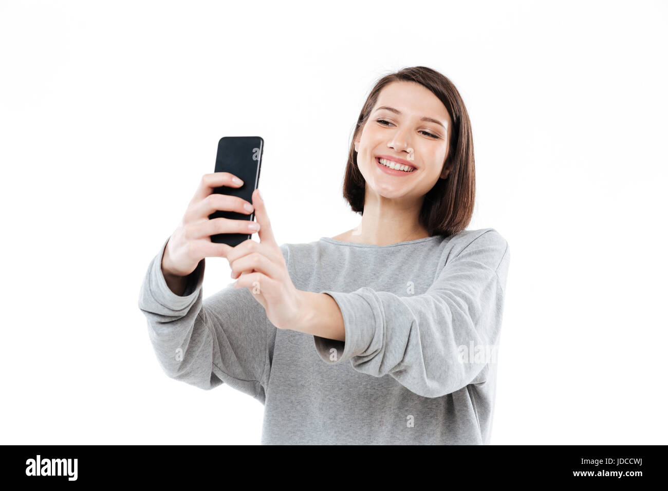 Happy smiling girl taking selfie on mobile phone isolated over white ...