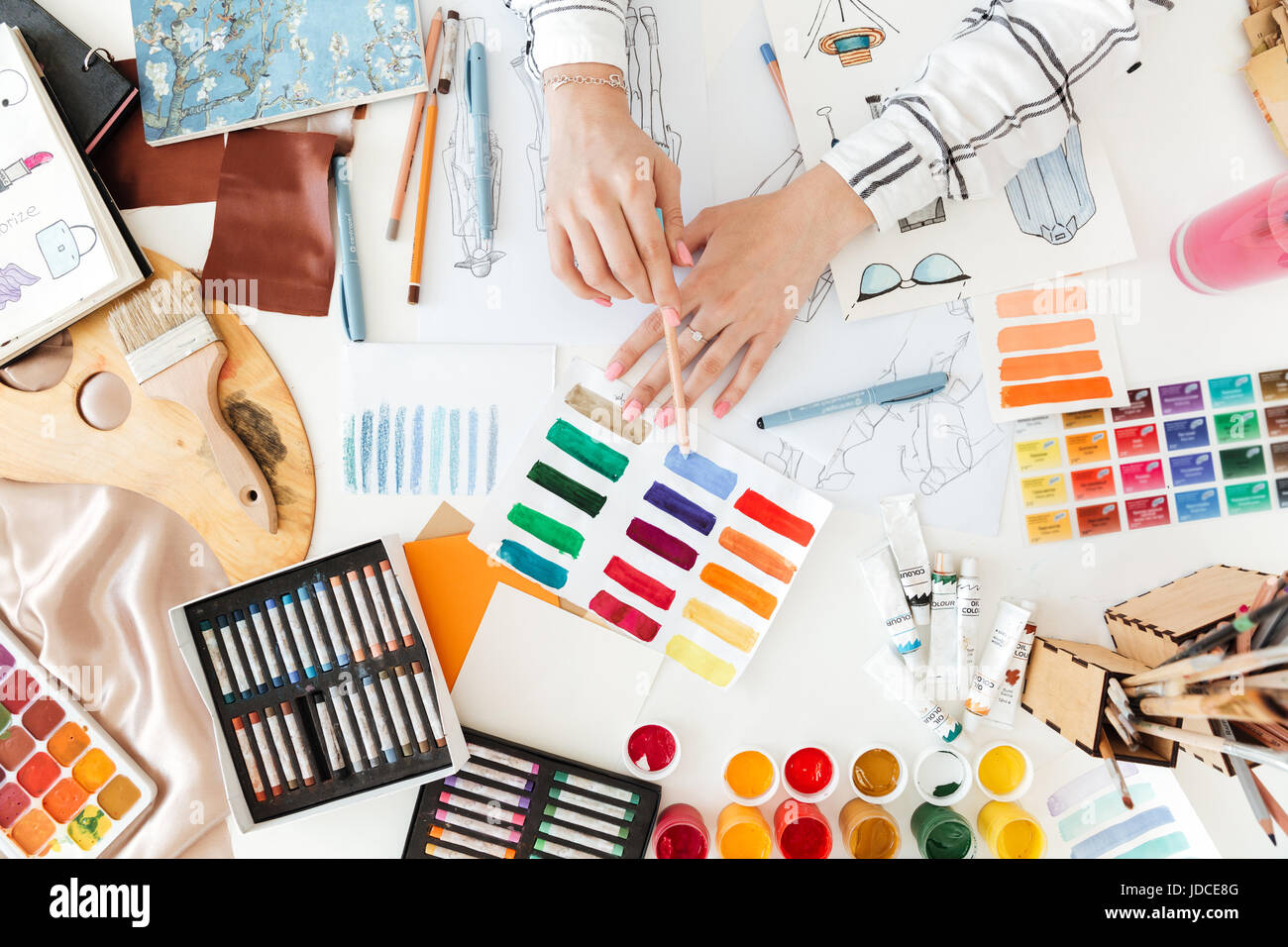 Top view of a female fashion designer working on sketches with paint on ...