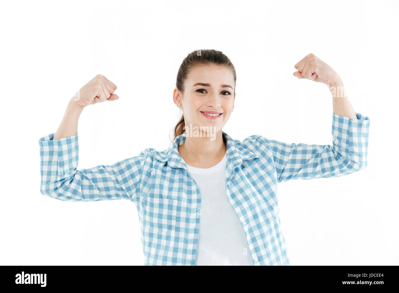 Young funny brunette girl wearing checkered shirt and jeans showing muscles isolated over white Stock Photo