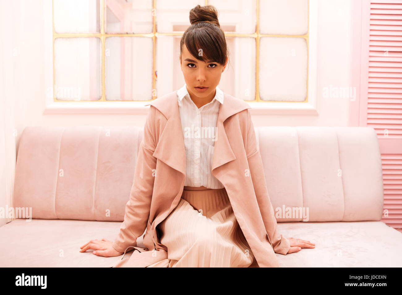 Portrait of a confident pretty woman sitting on a sofa indoors and ...