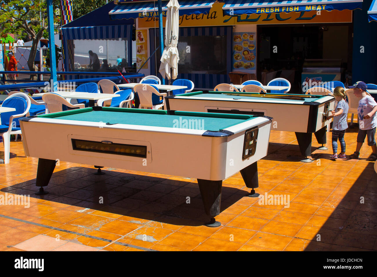Two young children playing around pool tables in a recreation area in a shopping mall precinct Stock Photo
