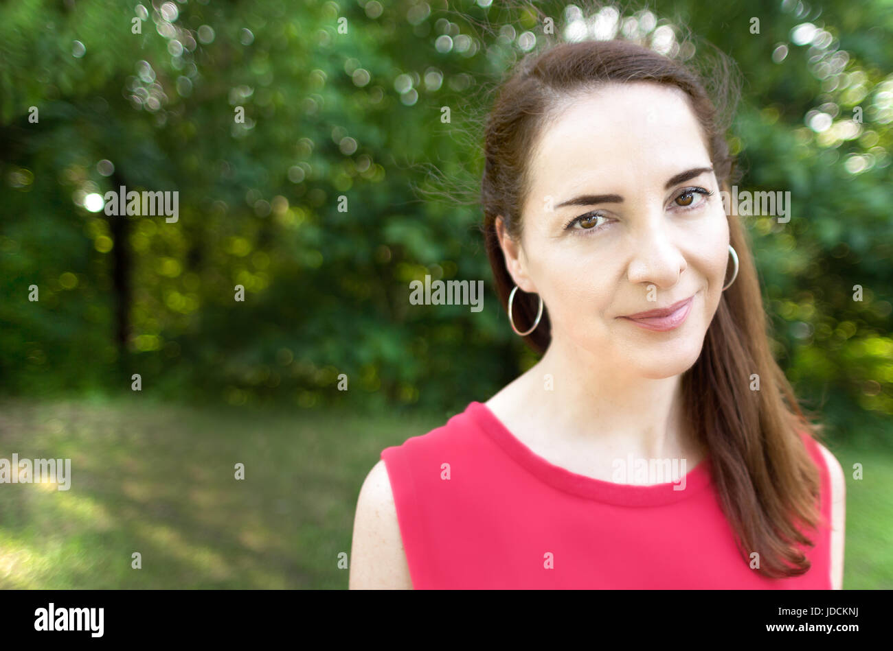Portrait of a woman looking at camera, outdoors at a park, natural light, expressive eyes. Stock Photo