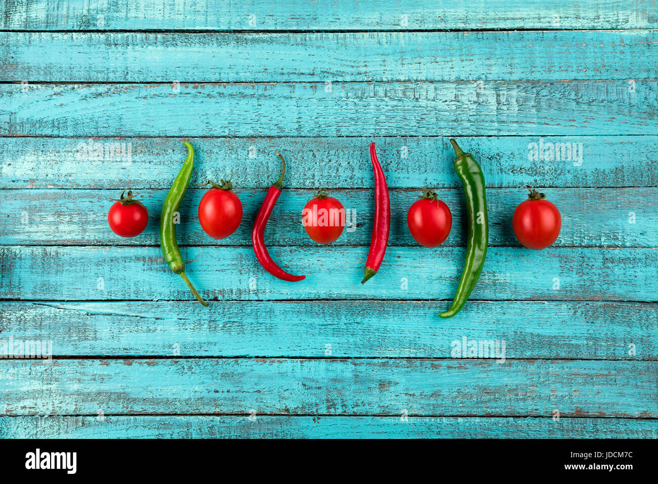 cherry tomatoes and chilli peppers on turquoise wooden table top texture. fresh seasonal vegetables concept Stock Photo