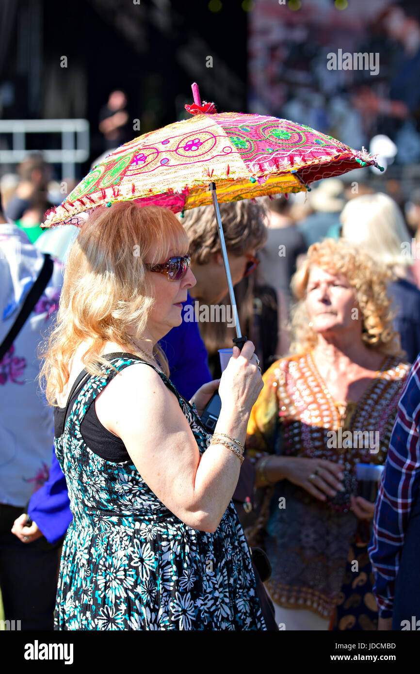 A woman taking shade under a parasol at the Africa Oye music festival in Sefton Park Liverpool Stock Photo