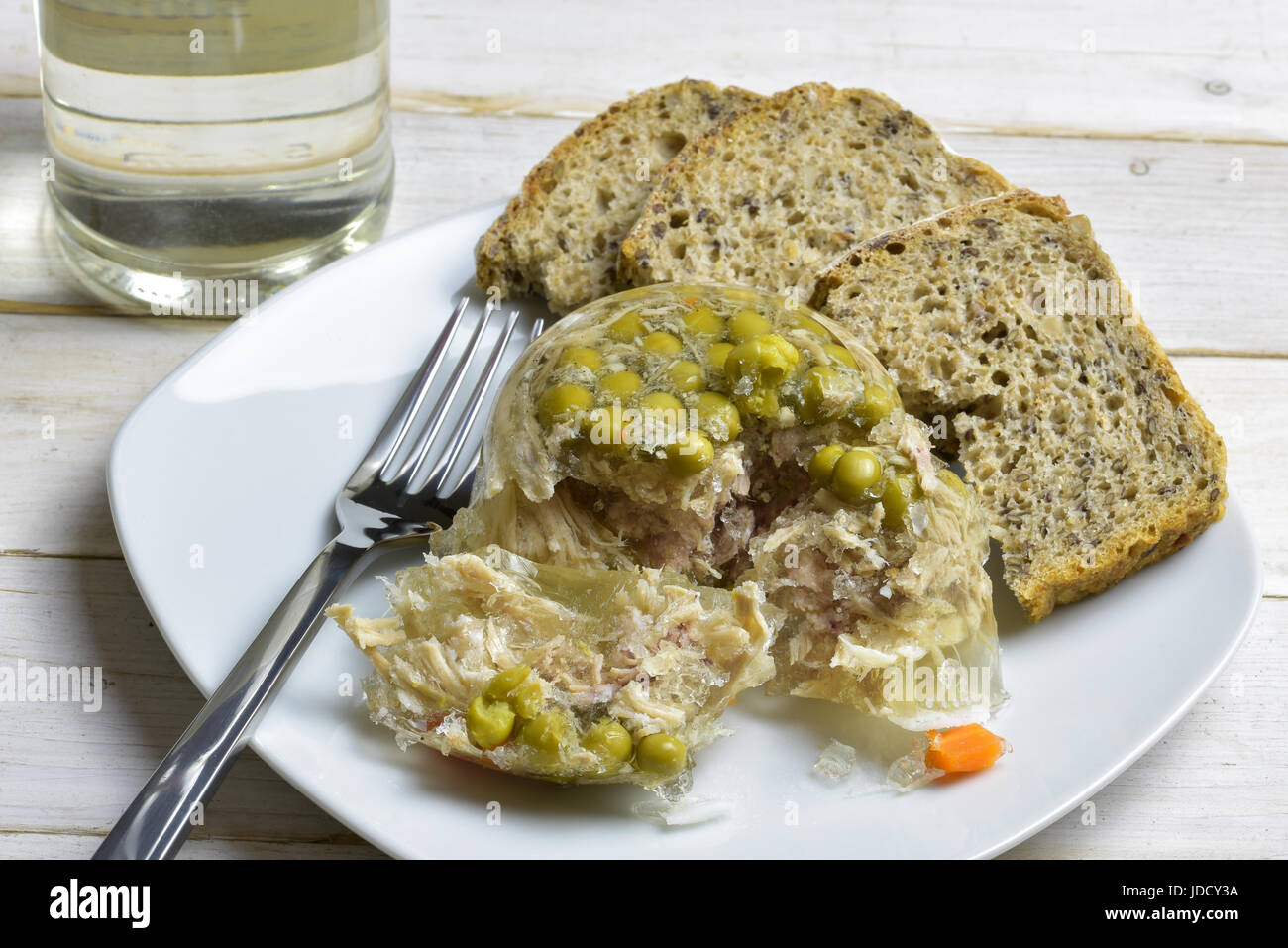 Polish appetiser  homemade jelly made with pork leg and pork trotters simmered together, served with vinegar and bread. Stock Photo