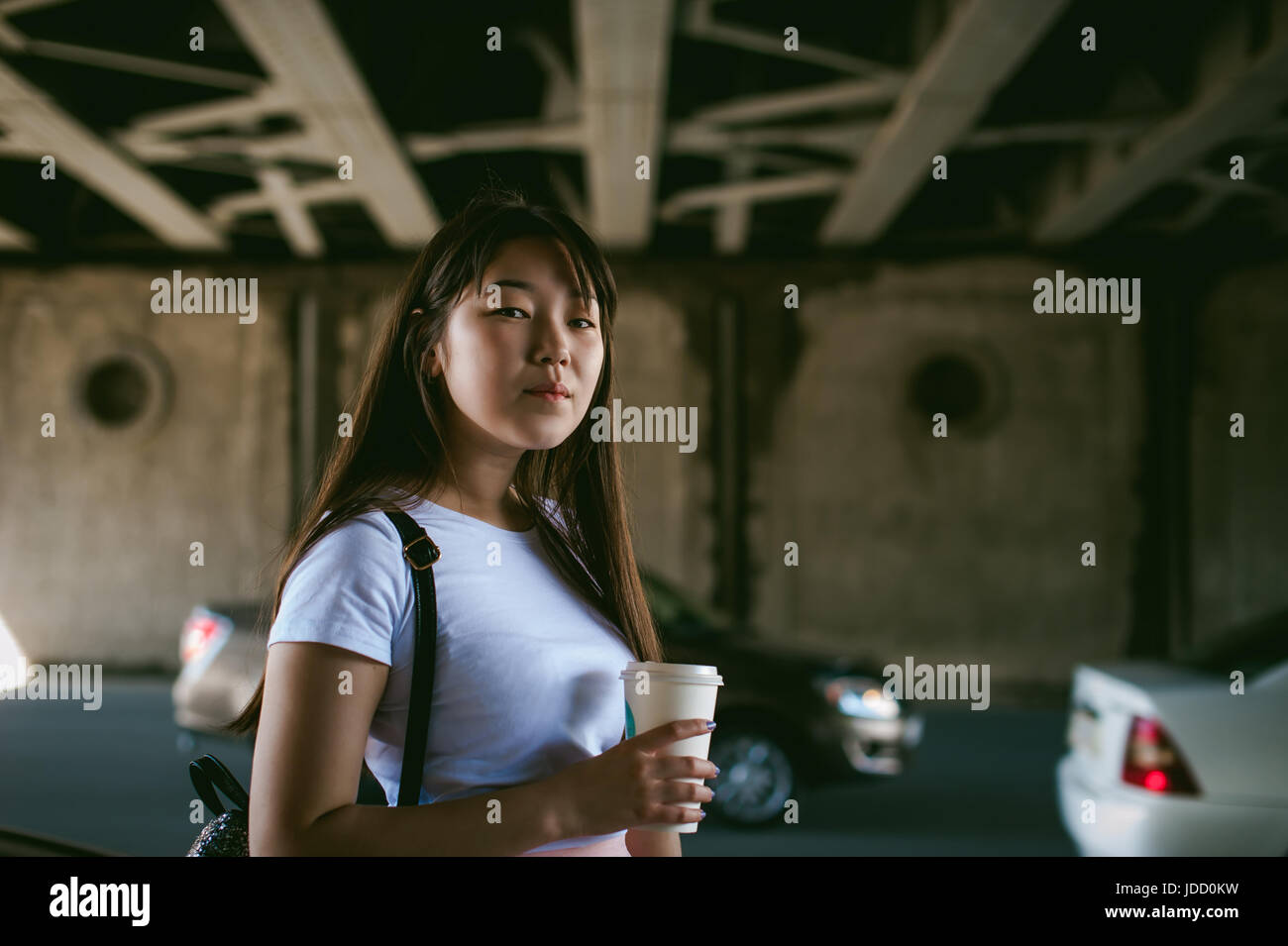 Cute asian young woman with a glass of takeaway, walks in an urban