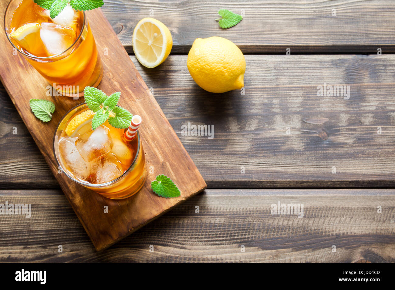 Iced tea with lemon slices, mint and ice cubes on wooden rustic ...