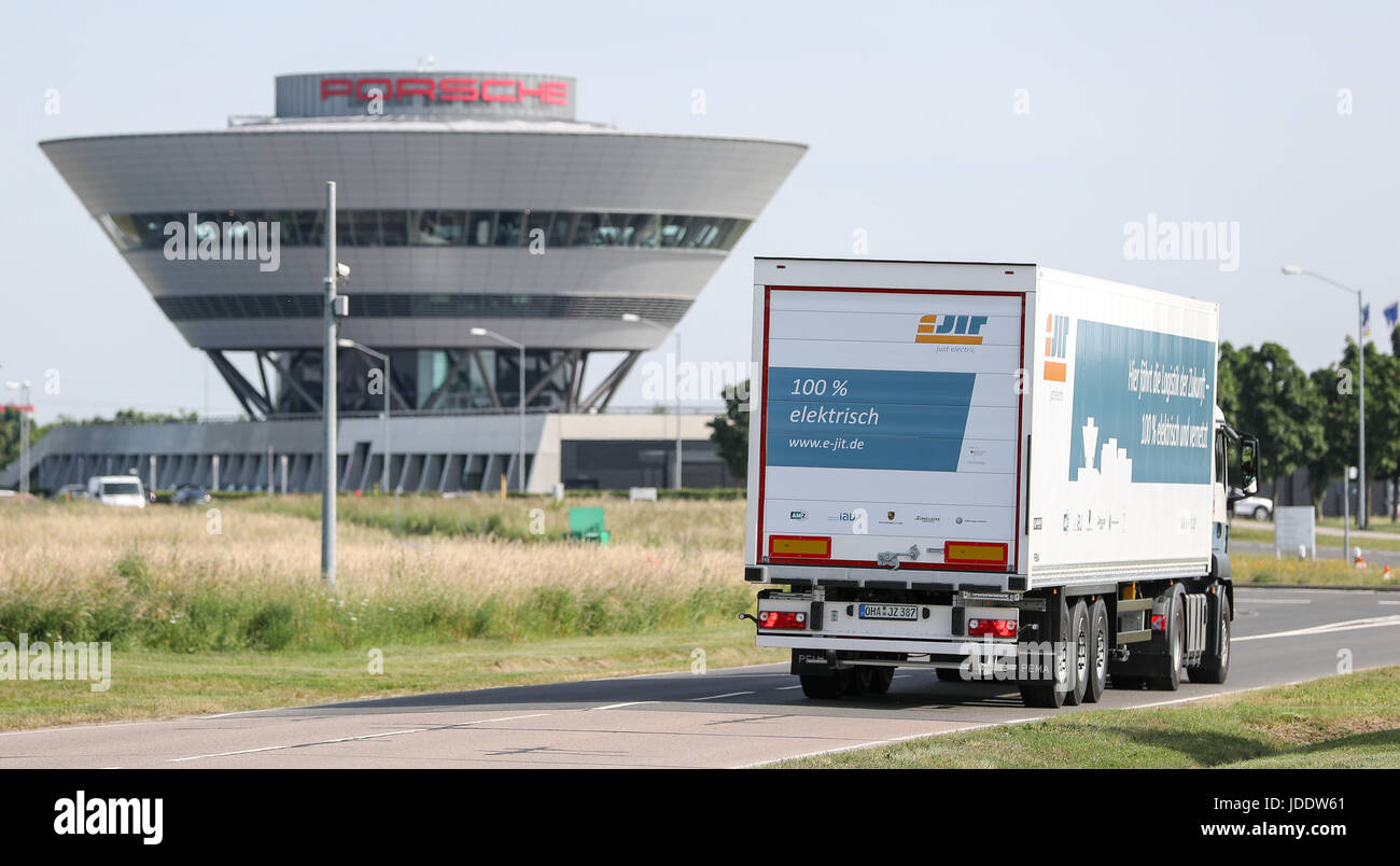 - ATTENTION EDITORS -PUBLICATION EMBARGO TUESDAY 20.06.2017 -20.30 - A fully electric, 40-ton trailer drives through the factory premises of Porsche, with the striking customer center in the background, in Leipzig, Germany, 15 June 2017. The research project eJIT developed, in cooperation with other companies, this first competitive electric trailer. Volkswagen's Zwickau Factory and Porsche Leipzig GmbG will be the first auto manufacturers in Europe to deploy the electric trailer in actual logistics operations. The two electric trailers reach speeds of up to 85 km/h with their 280 kilowatts of Stock Photo