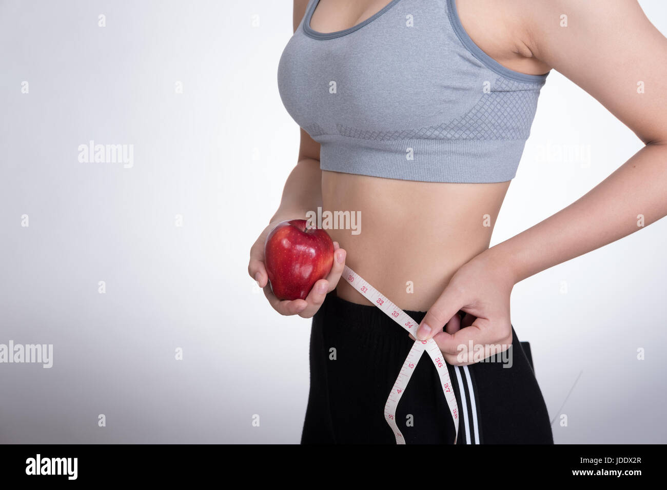 beautiful sporty fitness woman use measuring tape to measure the waist