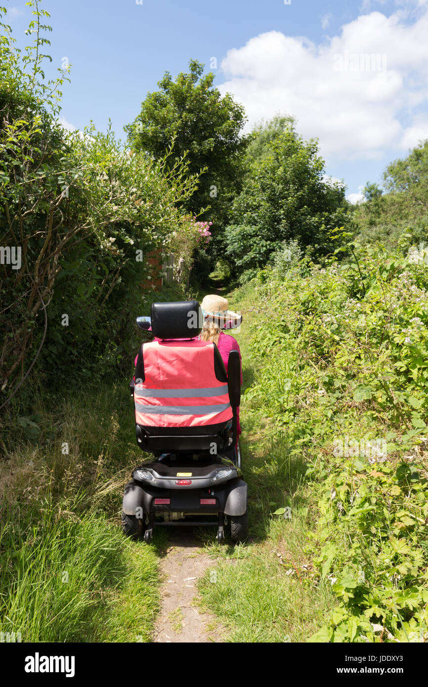 A woman riding a mobility scooter on a country path, giving  disabled access to the countryside, Kent, England UK Stock Photo