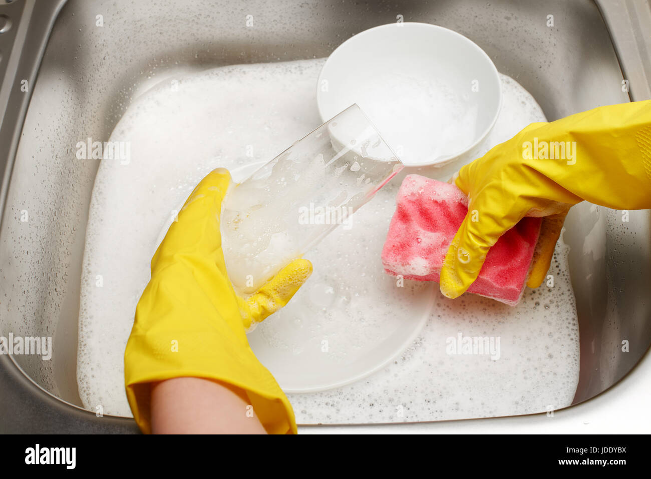 Close up of female hands in yellow protective rubber gloves washing ...