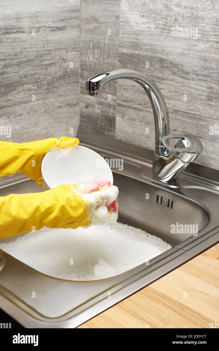 Close up of female hands in yellow protective rubber gloves washing ...