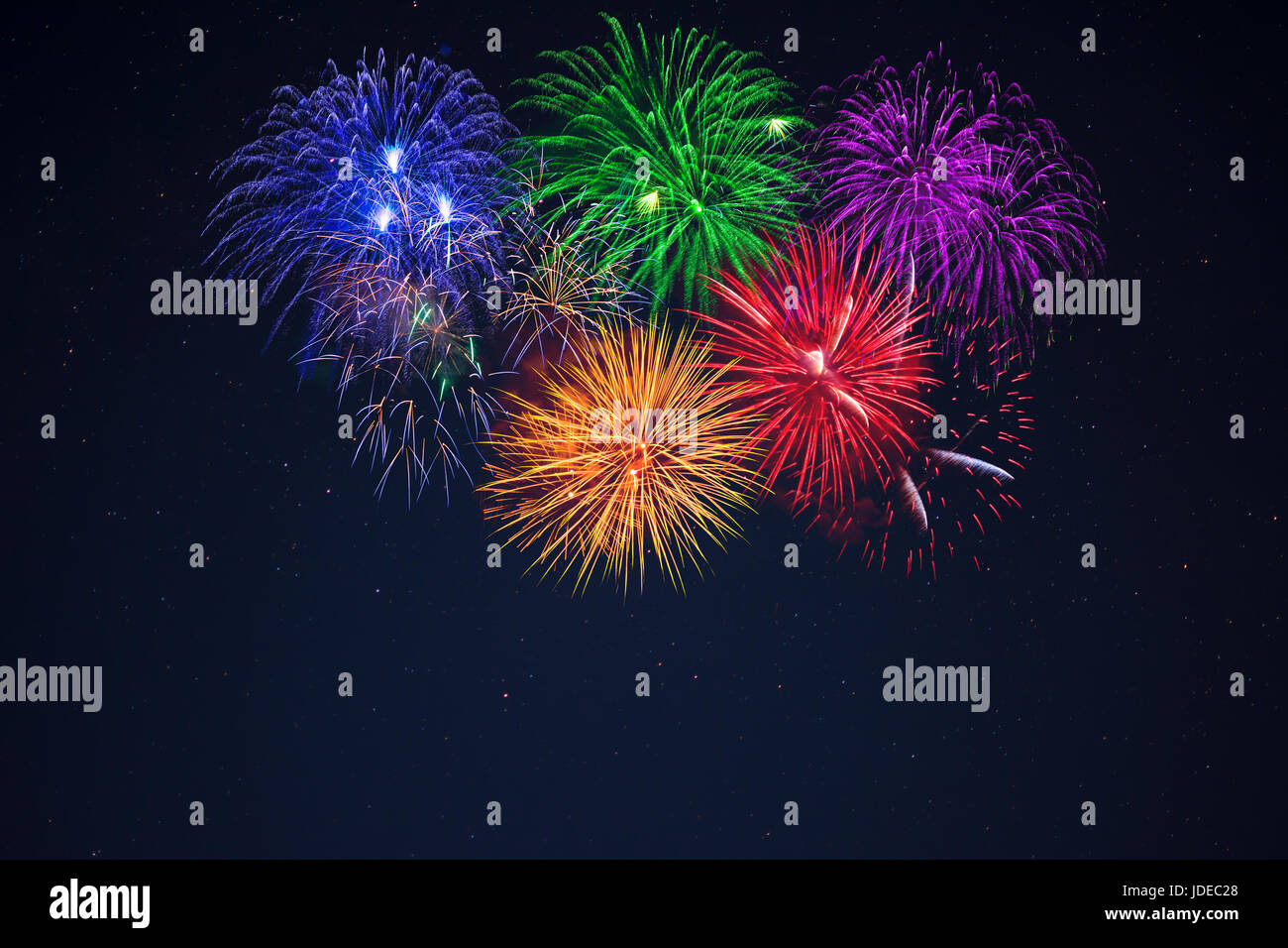 Sparkling blue green purple red yellow celebration fireworks over starry sky.  Independence Day, 4th of July, New Year holidays salute background. Stock Photo