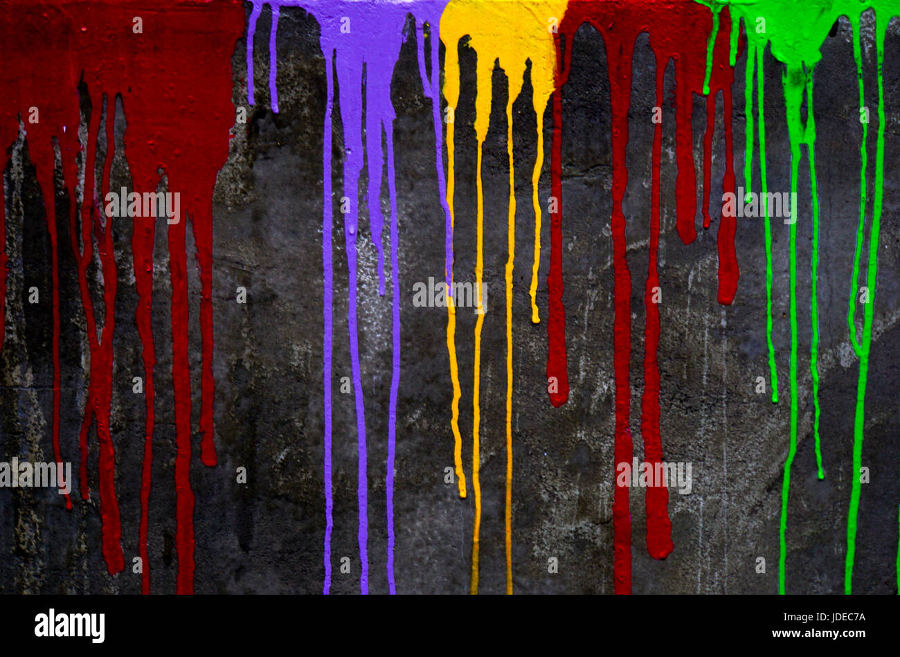 Colour paint drips down a black wall Stock Photo Alamy