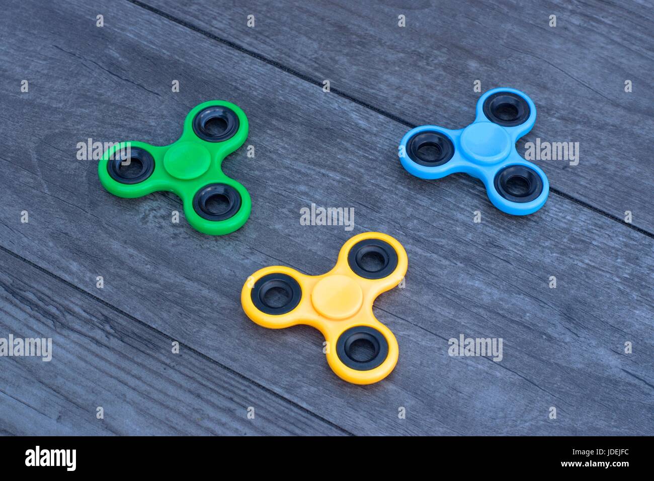 Three fidget hand spinner stress relieving toy on a wooden background ...