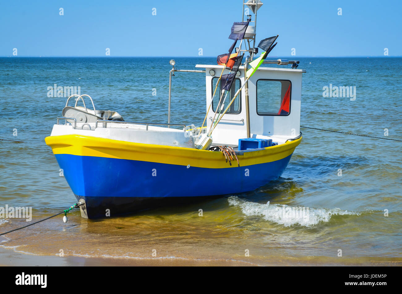 White yellow blue   fishing boat on alongshore Stock Photo