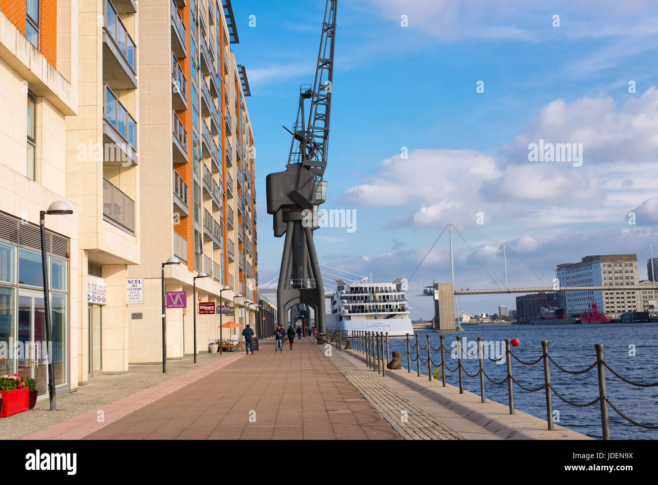 Riverside walk with big cranes and modern apartment buildings in Royal Victoria Dock, Excel Marina, Western Gateway, London, UK Stock Photo
