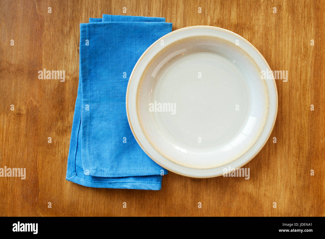 Overhead view of an empty cream colored plate and blue napkin Stock Photo