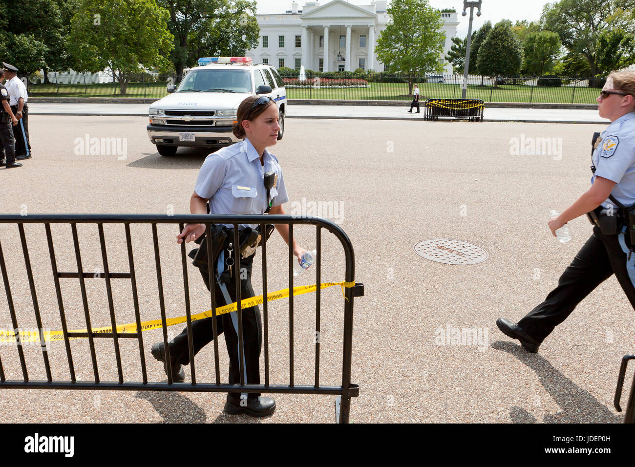 Policewoman moving police fence (barricade fence) in preparation of a public protest in front of the White House - Washington, DC USA Stock Photo