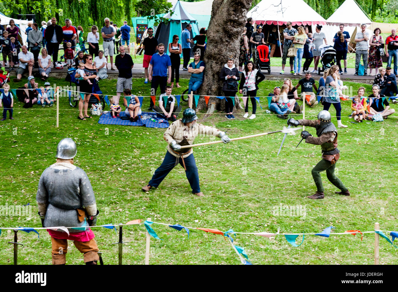 Medieval re-enactment event. Knights in armour fighting in small roped ...