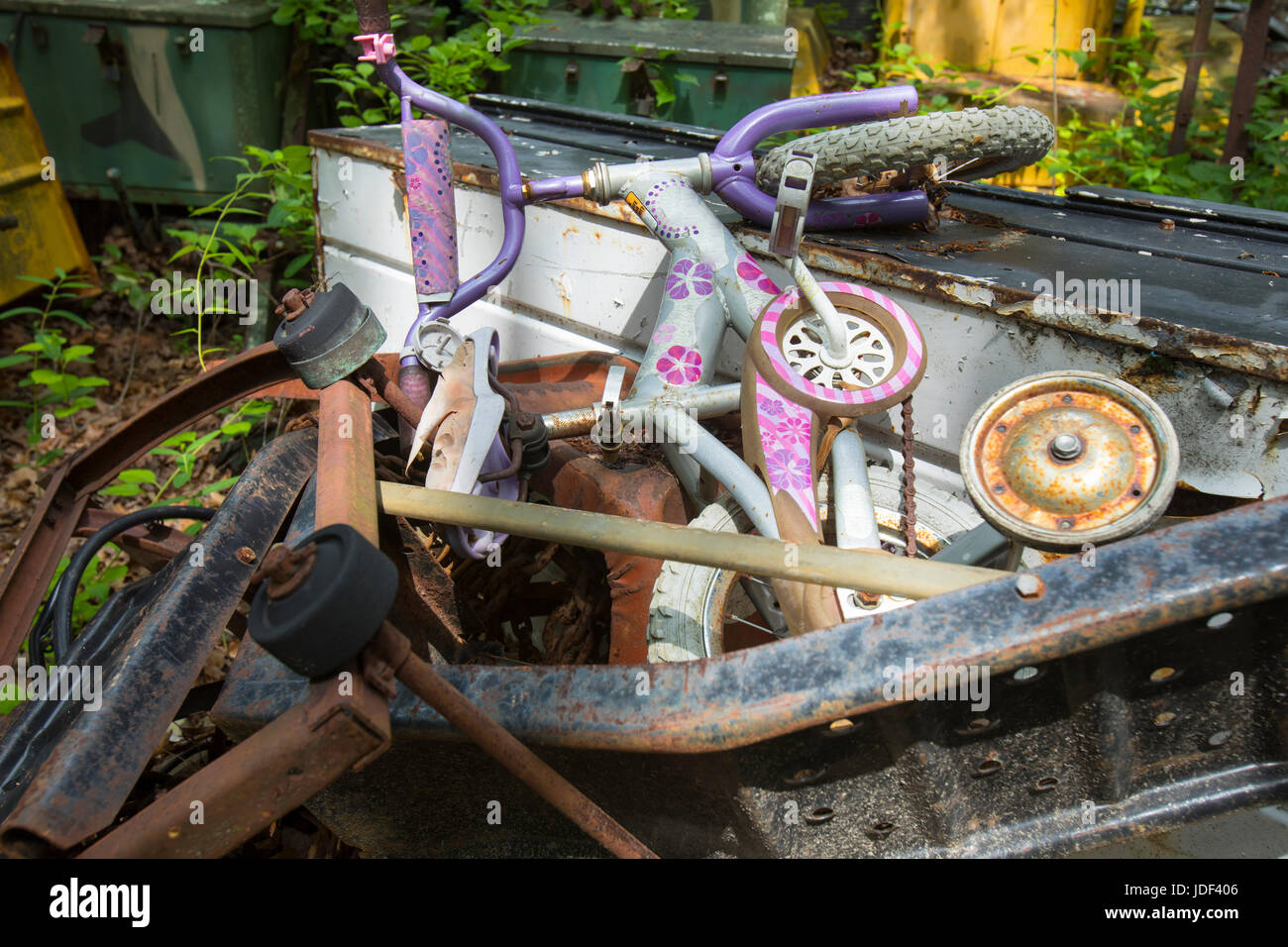 Kids bike with training wheels on top of scrap heap in junkyard Stock