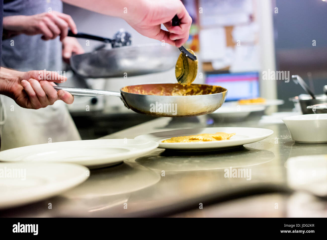 Chef serving pasta in an Italian restaurant kitchen spooning it from