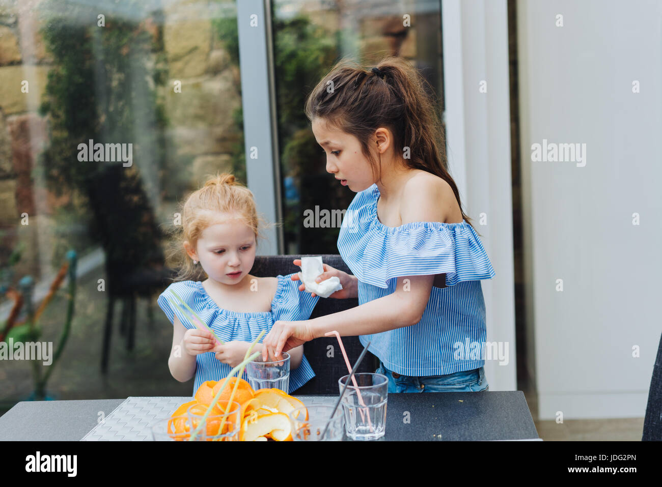 Two sisters drink juice in the kitchen Stock Photo Alamy