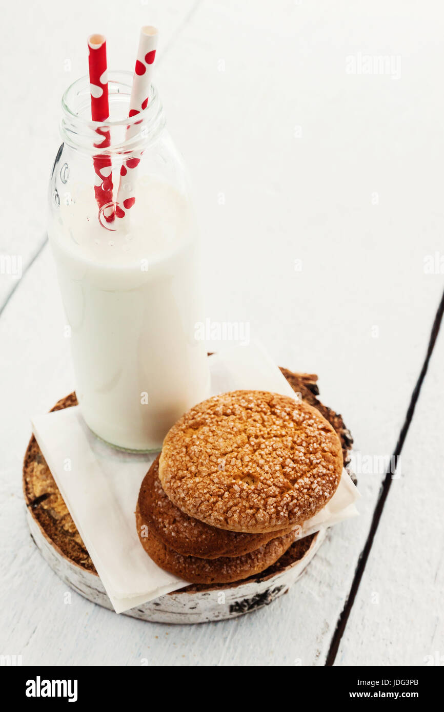 A stack of round shortbread cookies and a bottle of milk, on a white ...