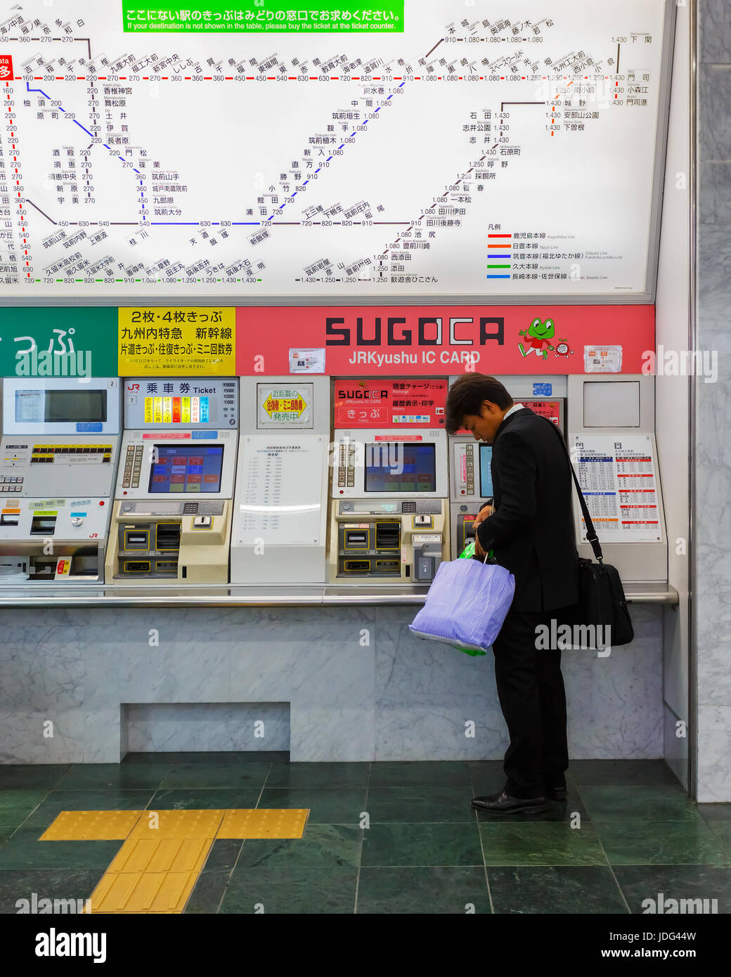 Unidentified man buys ticket from vending machine at Hakata Station in Fukuoka, Japan Stock Photo