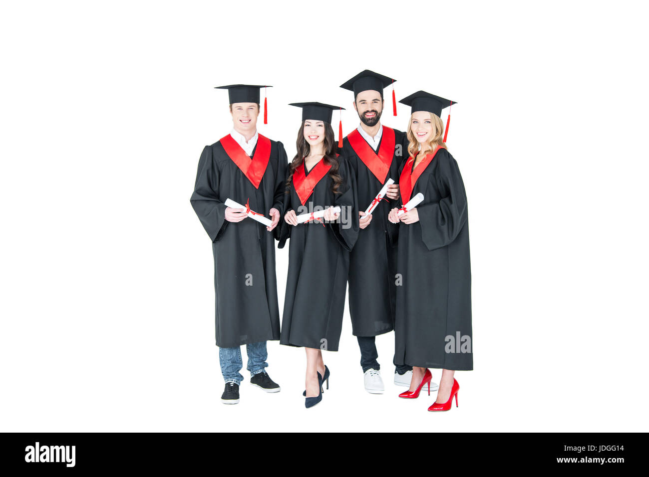 Full length front view of happy students in graduation caps holding diplomas on white Stock Photo