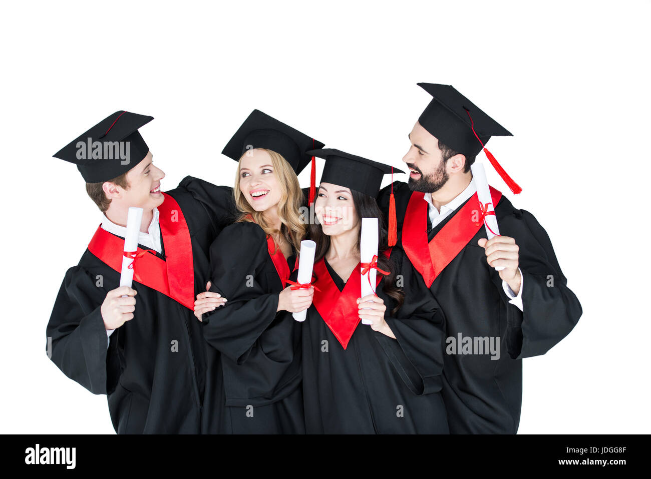 Happy students in academic caps standing embracing with diplomas Stock Photo