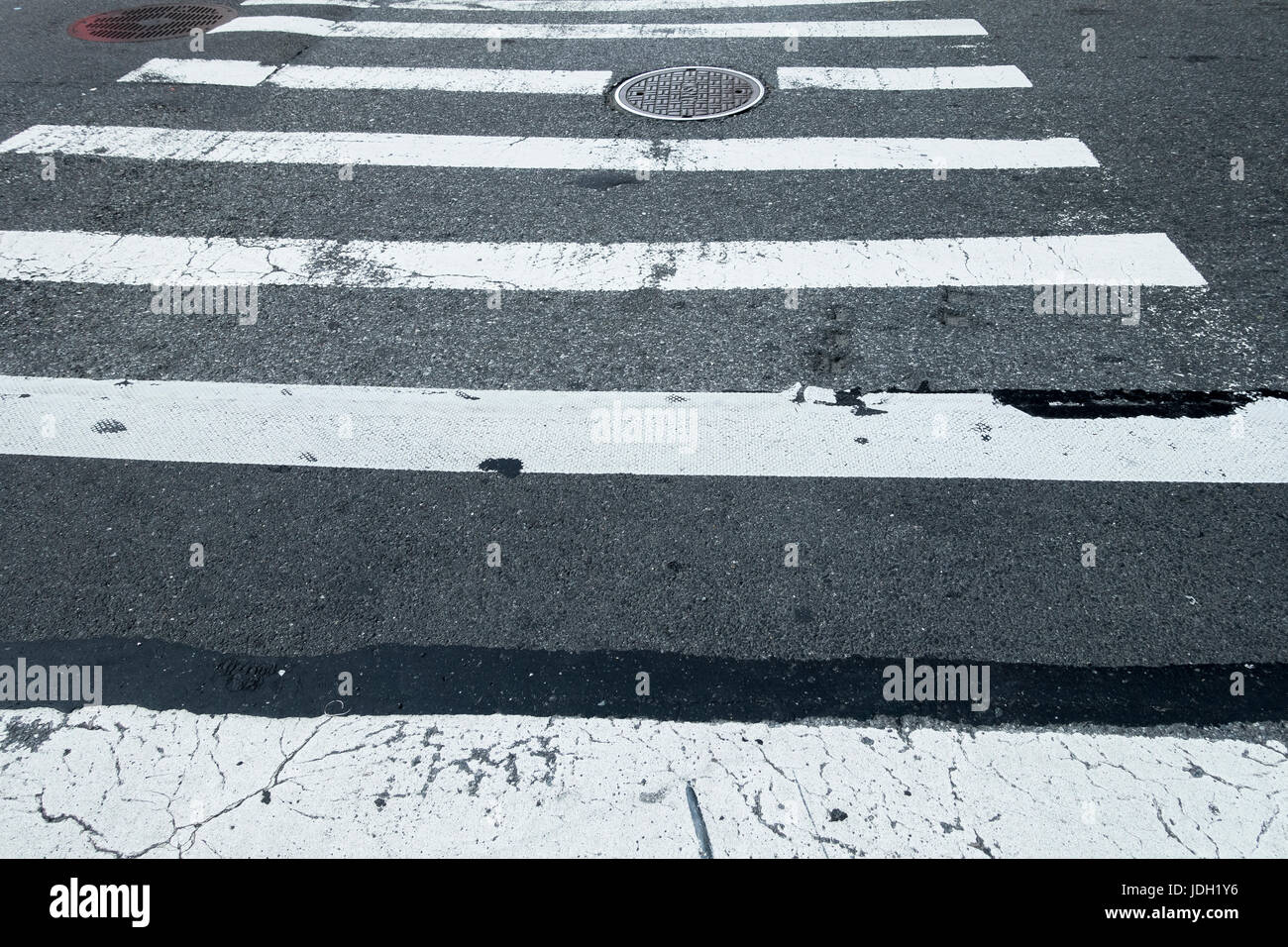 city crossing with white lines and manhole covers Stock Photo