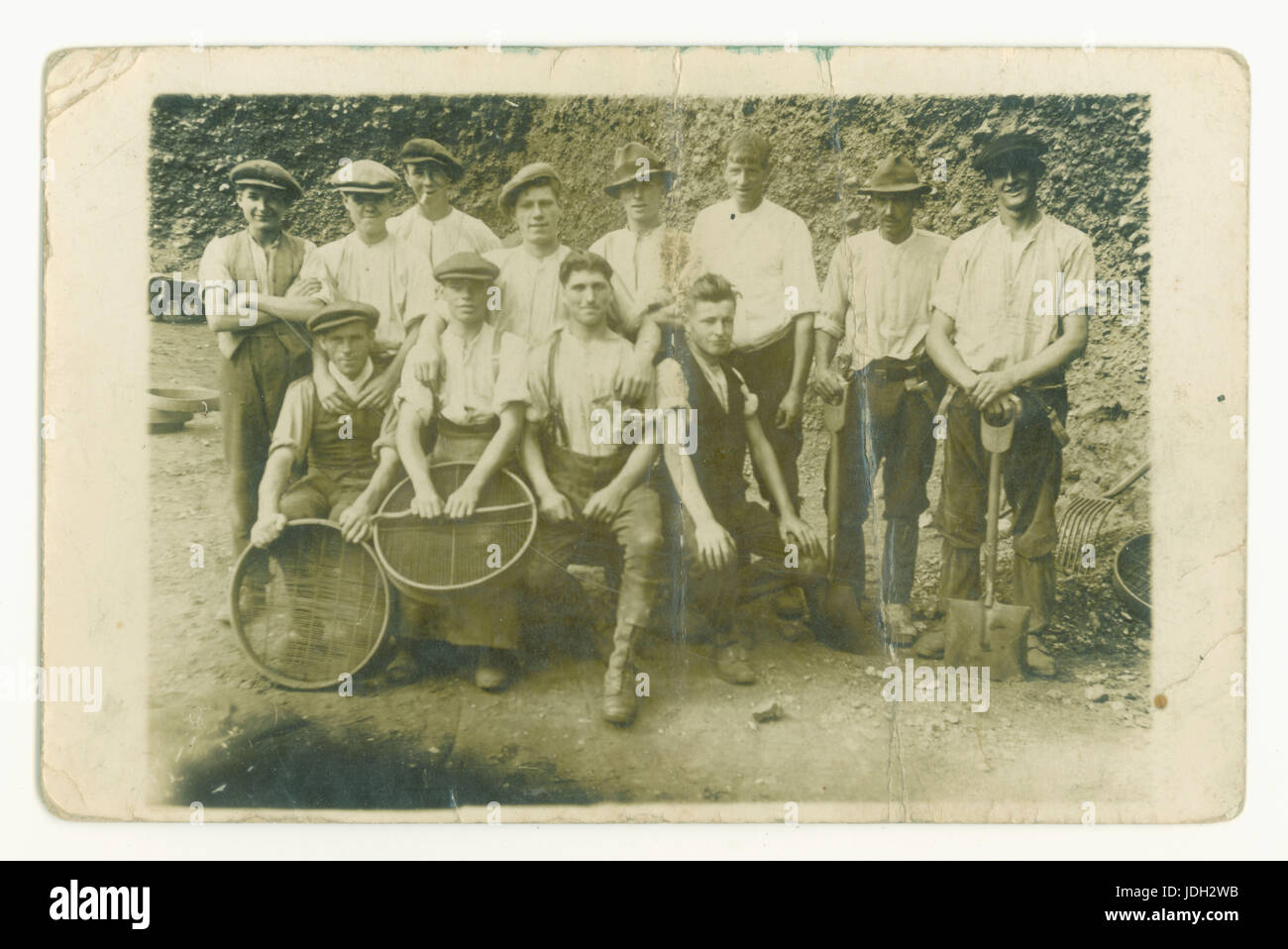 Early 1900's Edwardian historical postcard photo of young men working in a quarry holding sieves possibly used for screening aggregates into the required sizes, possibly for road building or construction, also with tools and shovels, circa 1905, UK Stock Photo