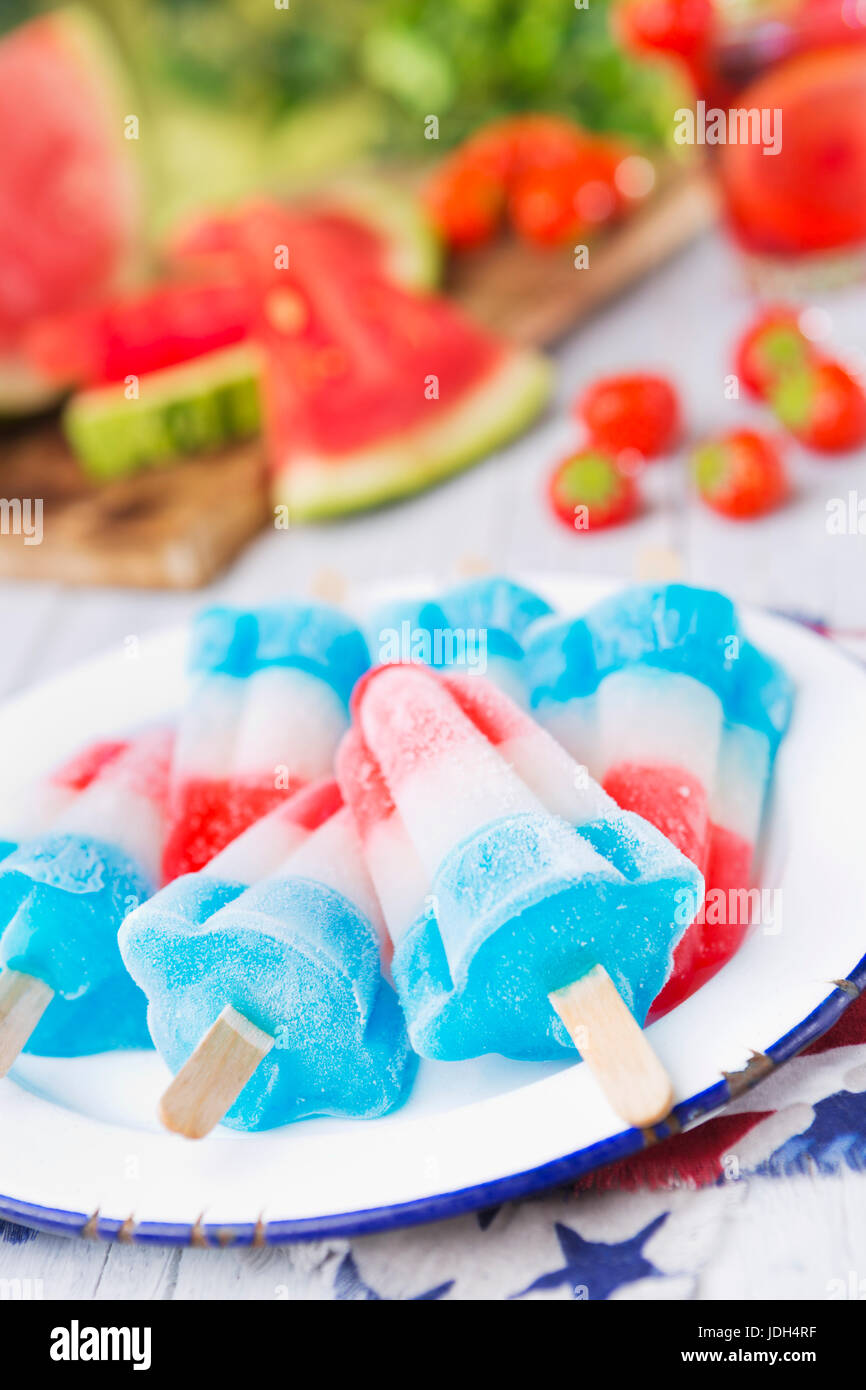 Homemade red-white-and-blue popsicles on an outdoor table with refreshing lemonade in the background. Stock Photo