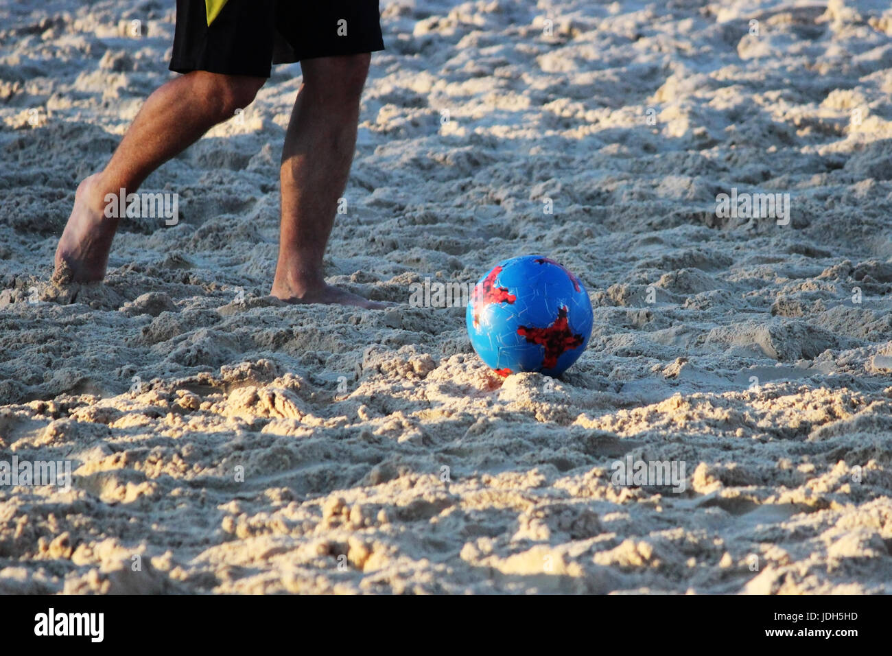 Young men play soccer in the summer on the sand platform Stock Photo