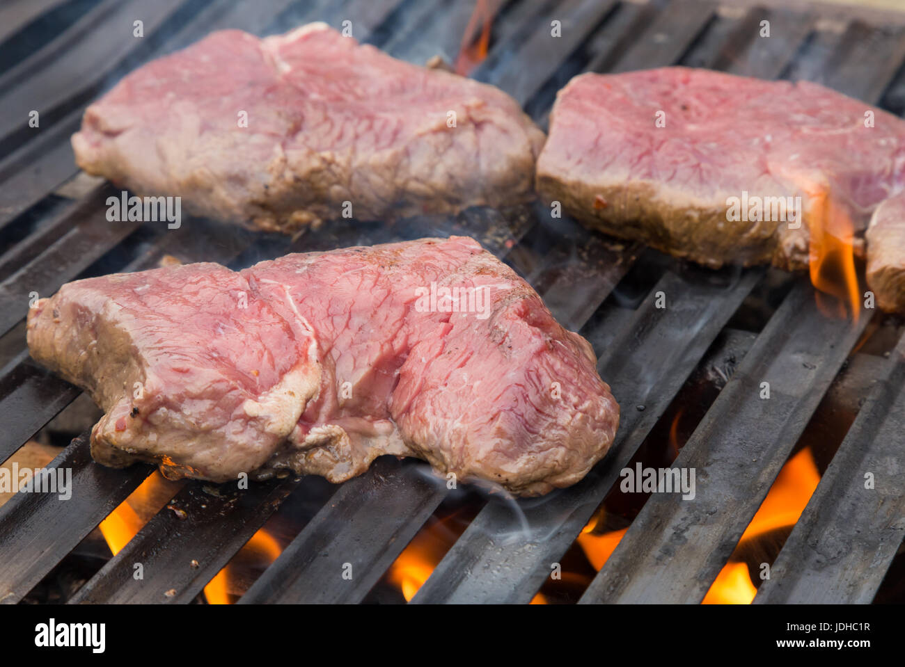 Raw beef steaks on the grill with flames Stock Photo Alamy