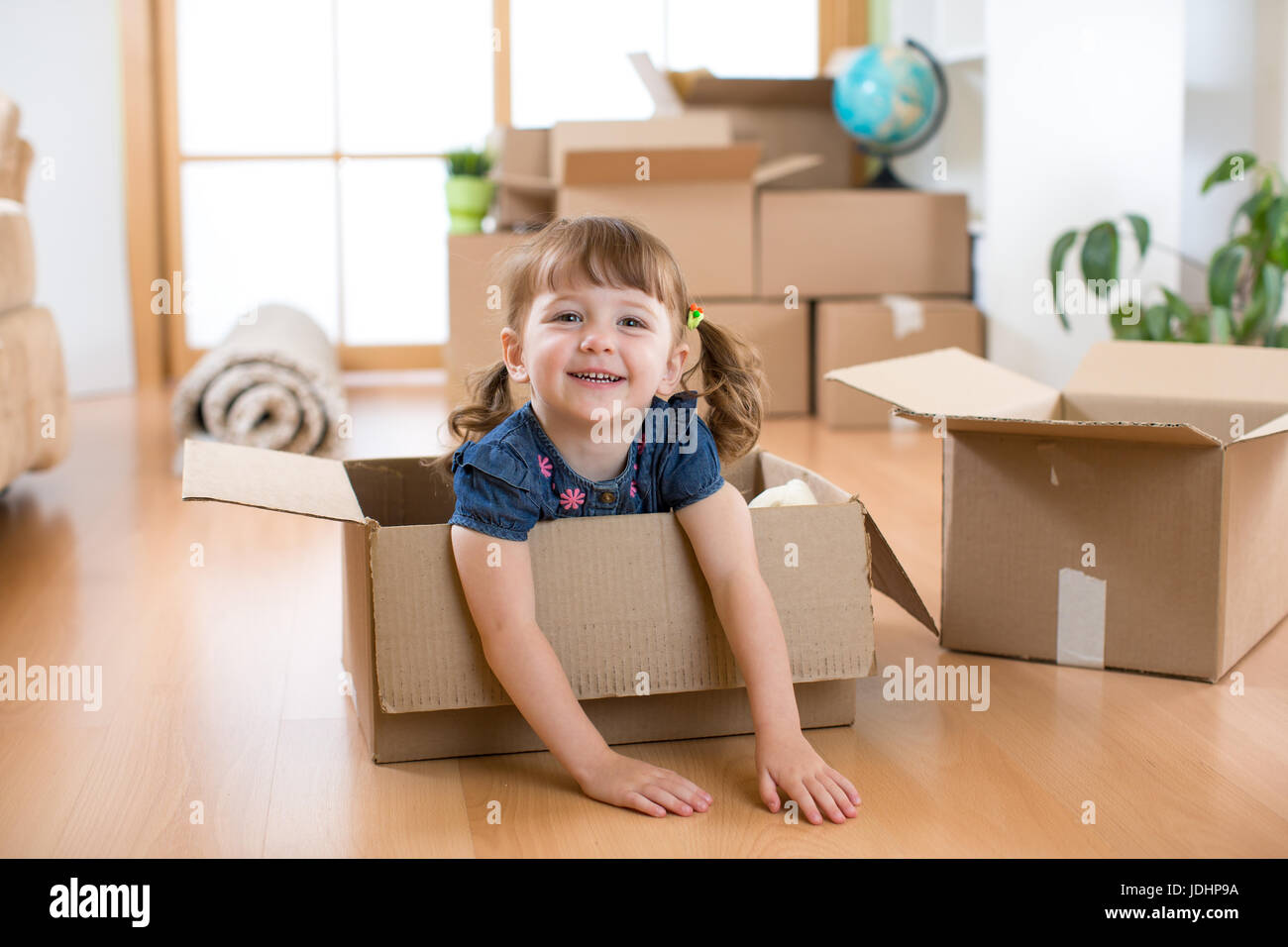 Just moved into a new home. Child into cardboard box. Stock Photo