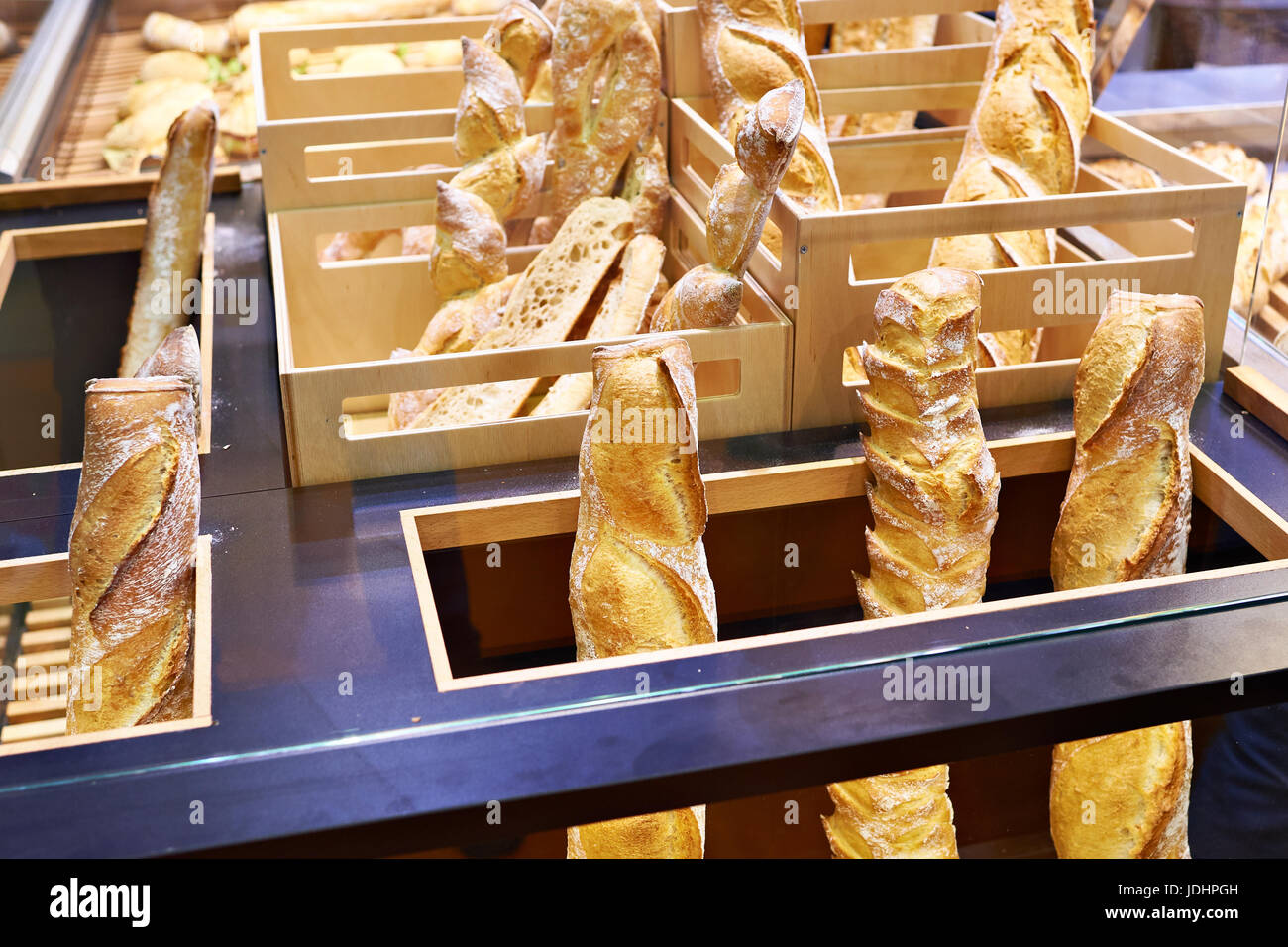 Fresh baguettes of white bread in wooden boxes on the counter of the