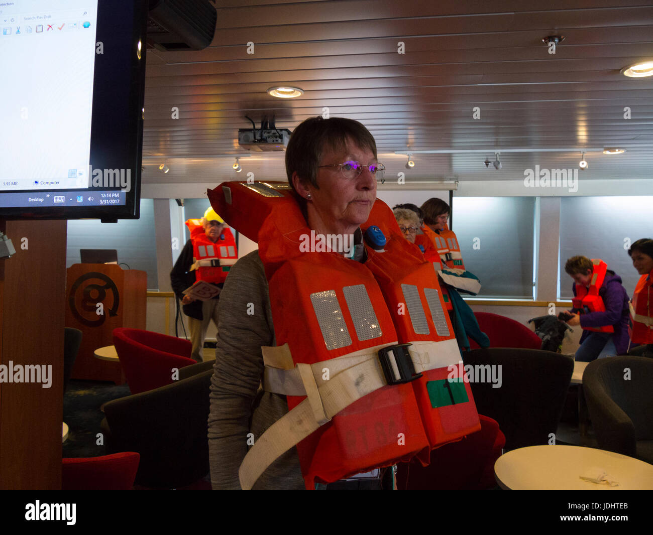 Cruise ship passengers wearing life jackets for safety drill waiting in