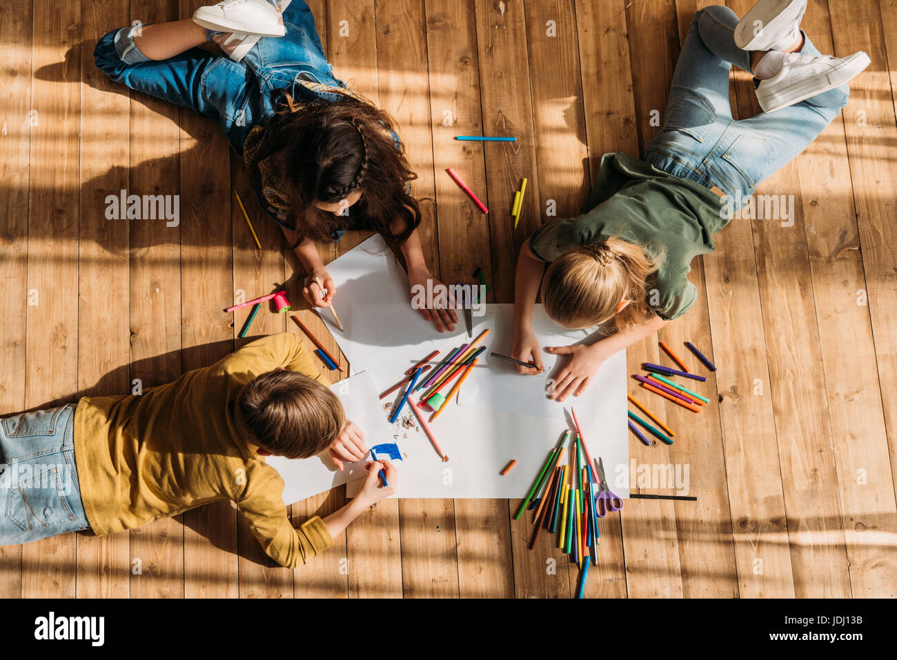 cute kids drawing on paper with pencils while lying on floor Stock ...