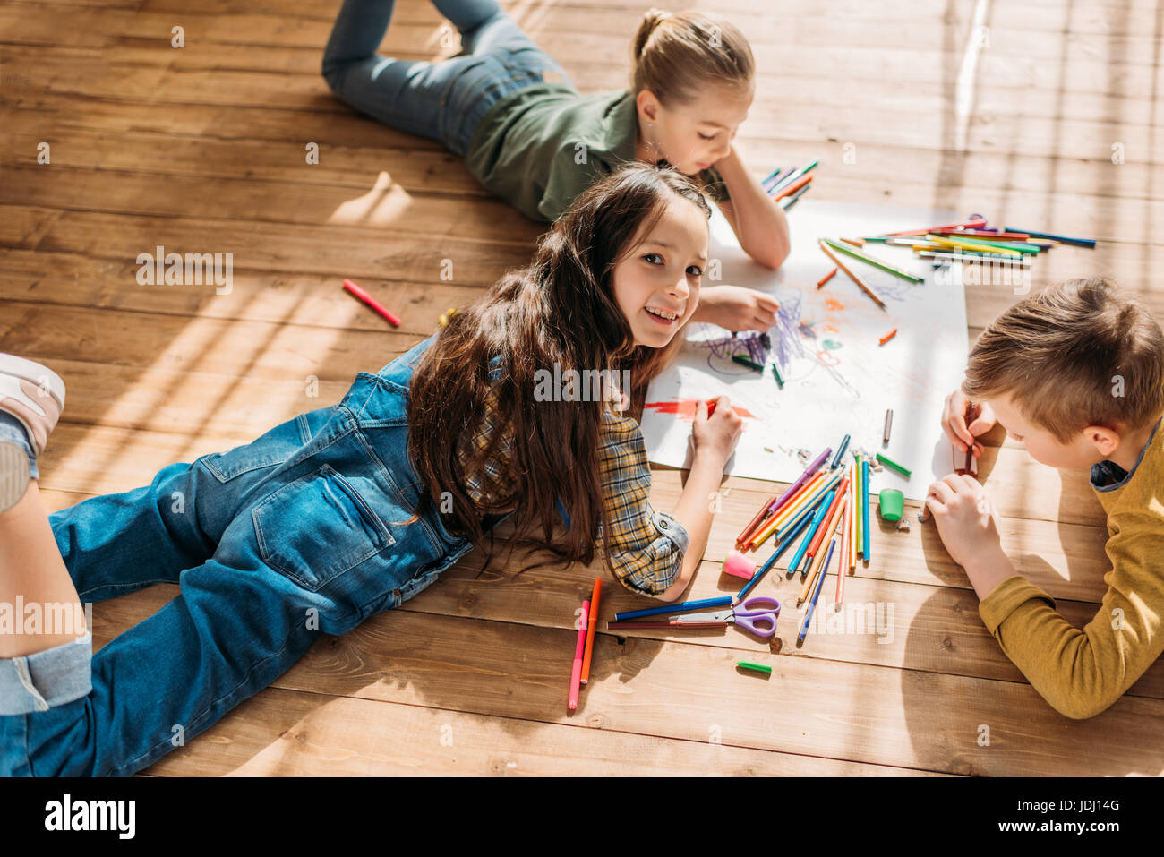 cute kids drawing on paper with pencils while lying on floor Stock ...