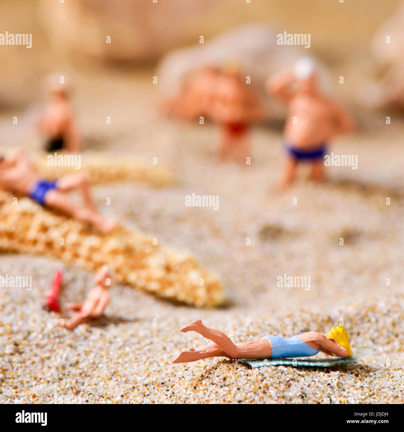 some different miniature people wearing swimsuit on the sand of the beach Stock Photo